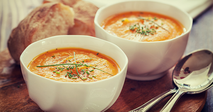 Two bowls of butternut squash soup with bread