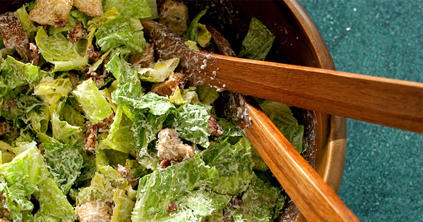 Caesar salad in a bowl with tongs