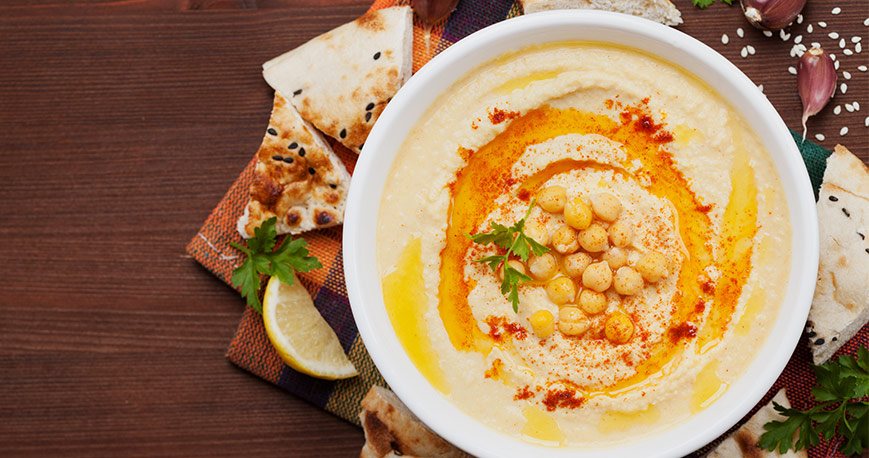 Hummus in a bowl with pieces of pita surrounding