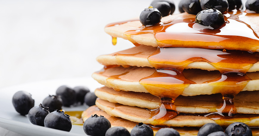 Stack of pancakes with blueberries and syrup on top