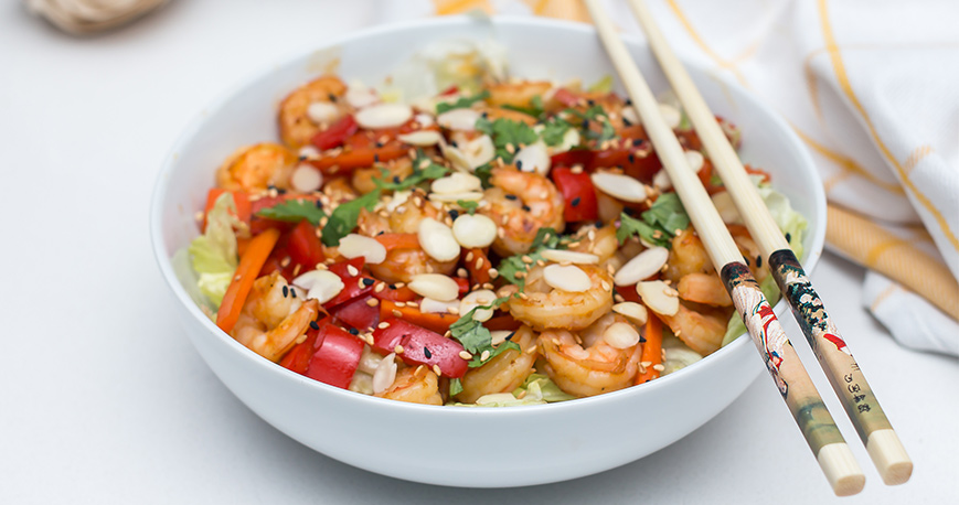 A salad with shrimp in it and chop sticks resting on bowl